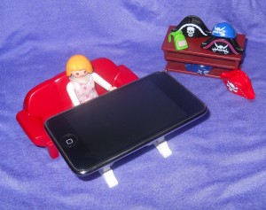 A playmobil figure sits in front of an iPod.